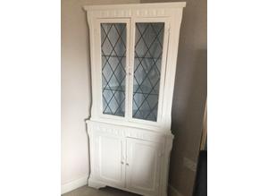 French farmhouse style wood display corner unit with glass shelves.